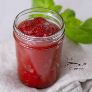 square crop of a glass jar filled with ketchup.