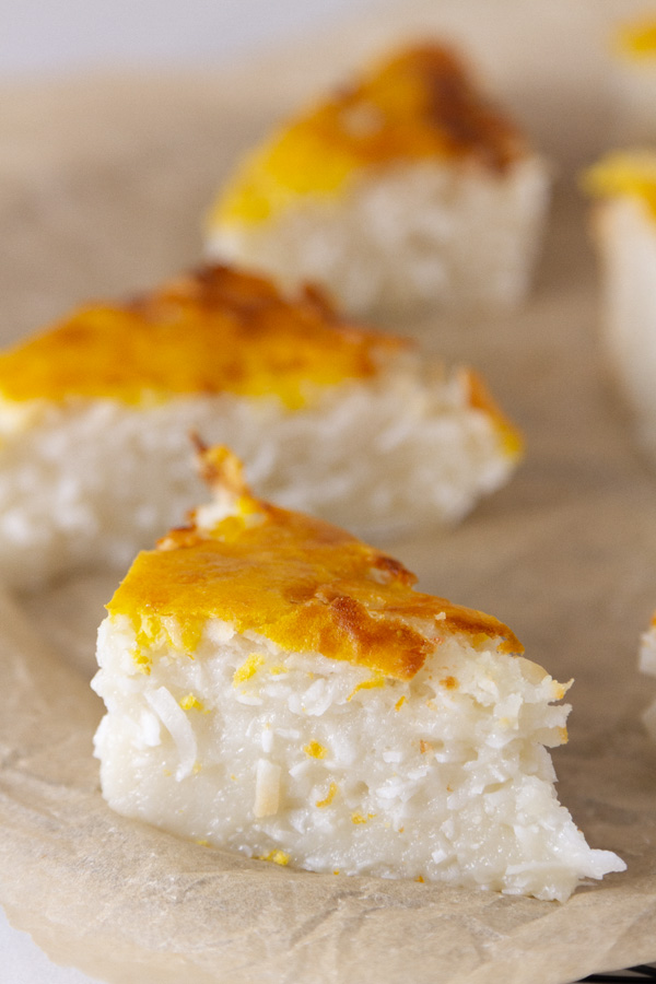 coconut cake cut into triangles and served on parchment paper.
