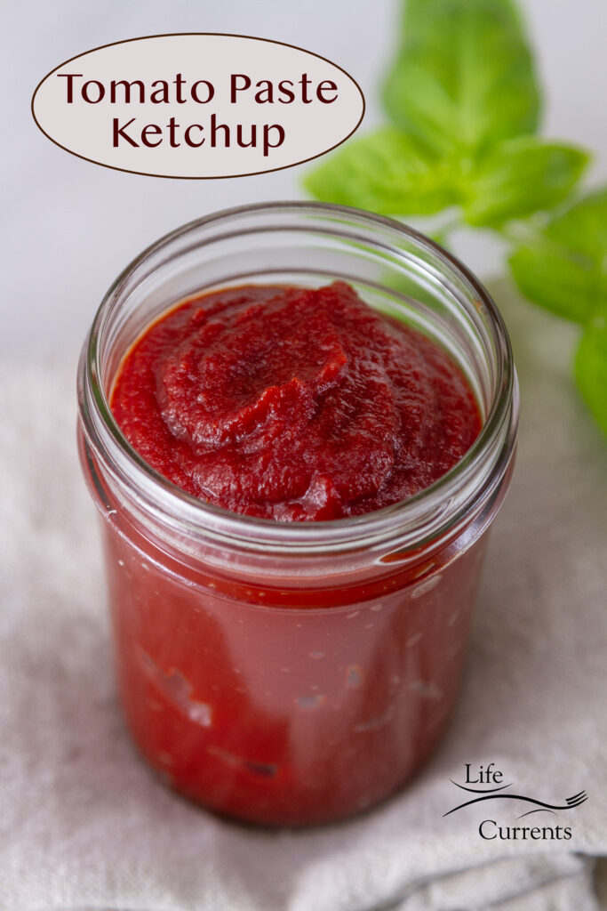 a small glass jar with ketchup inside, fresh basil in the background, and title on image: Tomato Paste Kecthup.