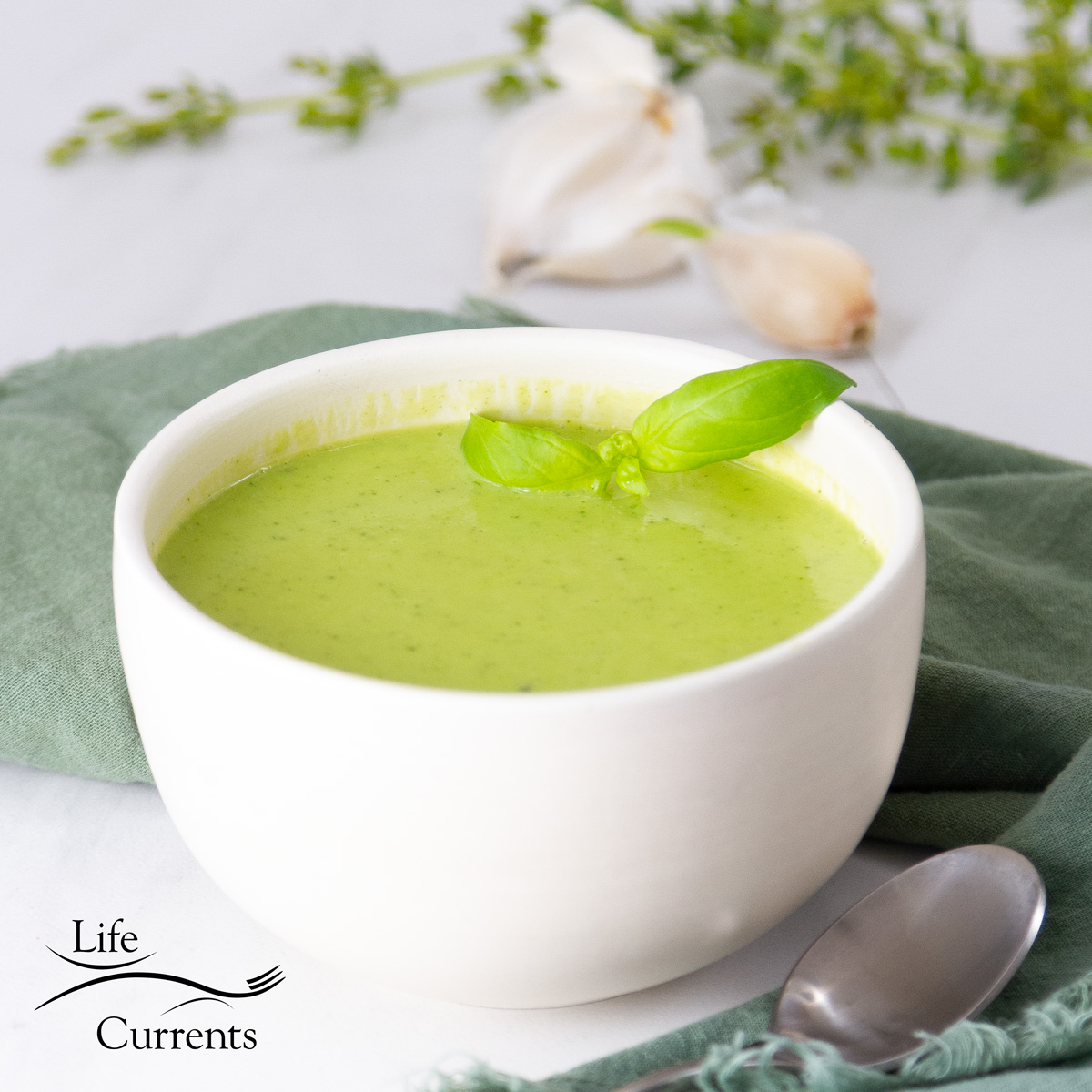 square crop of a white bowl with green soup in it.