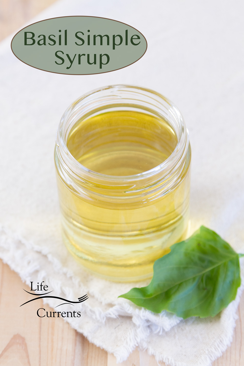 a glass jar of basil simple syrup with a fresh basil leaf, title on image.