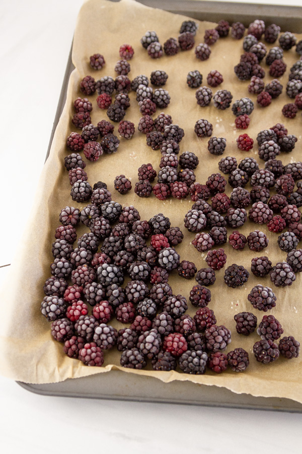 frozen blackberries on a parchment paper lined baking tray.
