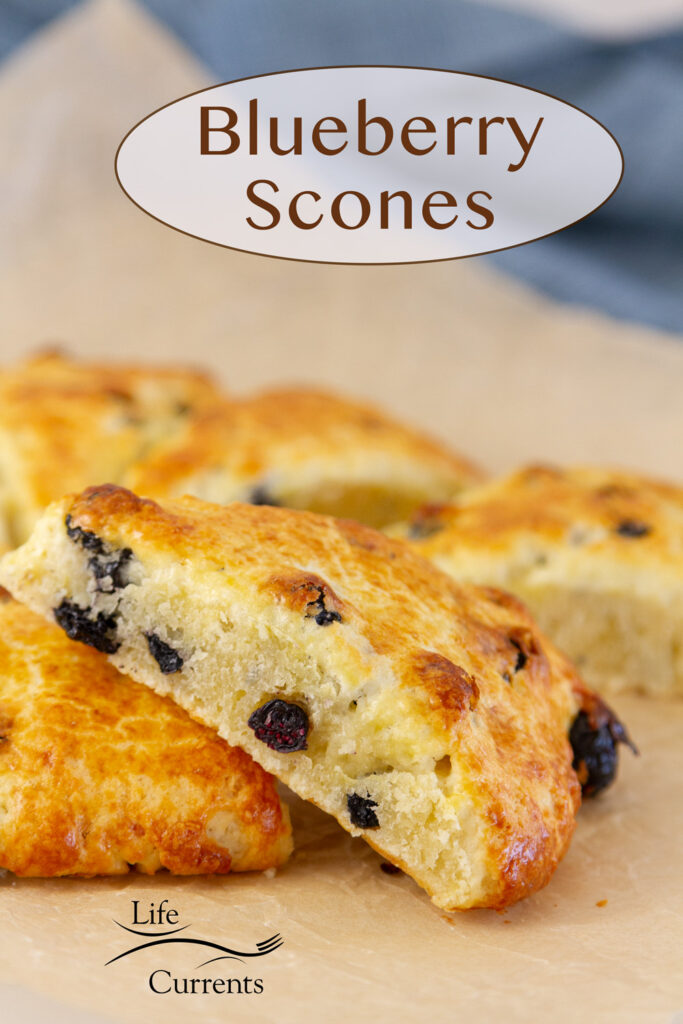a scone leaning on more baked scones, title on upper right: Blueberry Scones