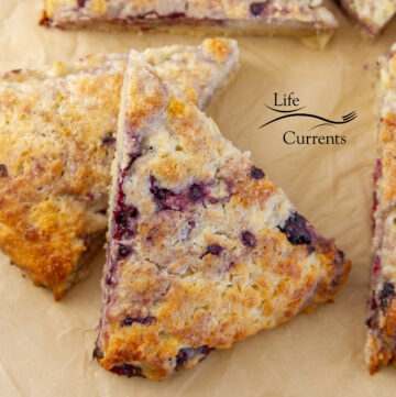 two blackberry scones stacked on parchment paper.