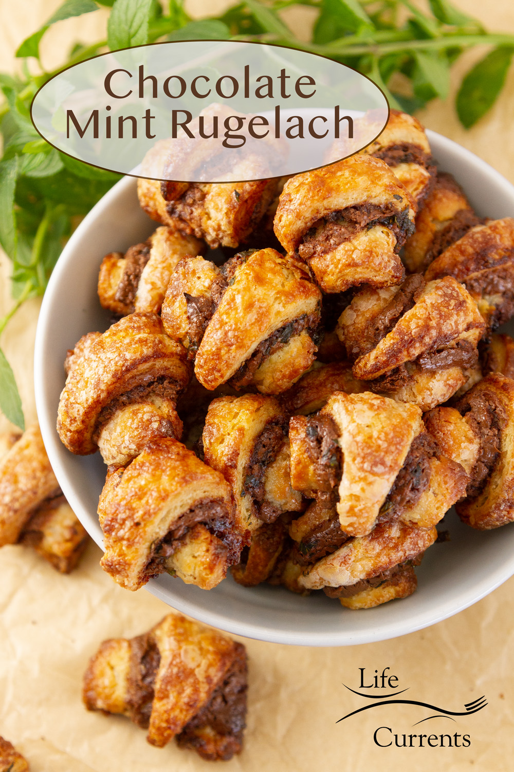 Chocolate Mint Rugelach in a bowl with a couple of cookies next to it, and some fresh mint in the background.