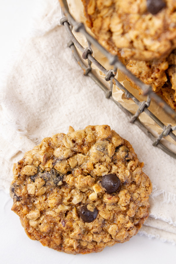 looking down on a cookie on a cloth napkin that's next to a container of other cookies.