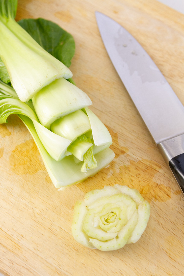 bok choy with the root end cut off and a knife next to it.