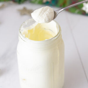 whipped cream in a mason jar with a spoonful being held above it.