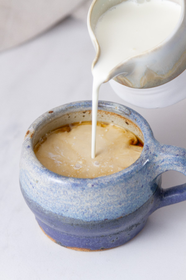 cream being poured into a mug of coffee.