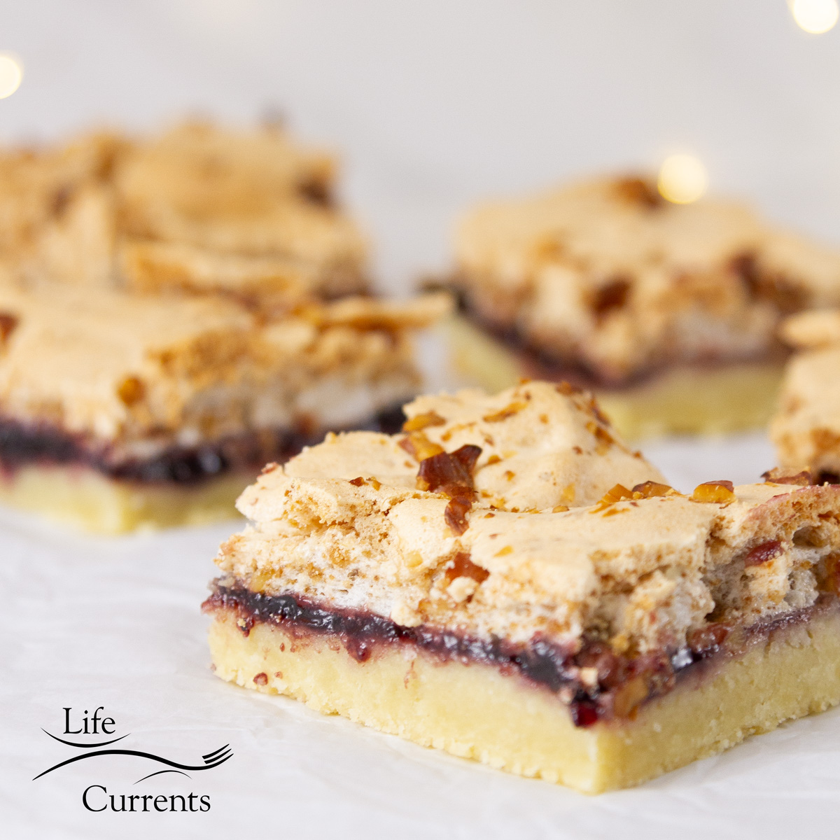 square crop of bar cookies cut up into squares on parchment paper with twinkle lights in the background.