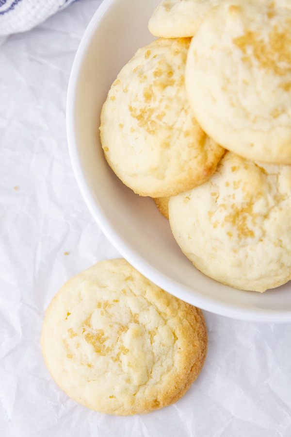 looking down into a bowl filled with cookies and one is next to the bowl.
