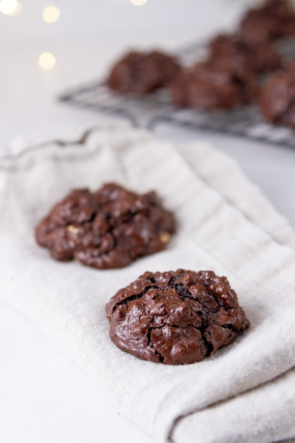 Two cookies on a cloth napkin in front of a rack of cookies.