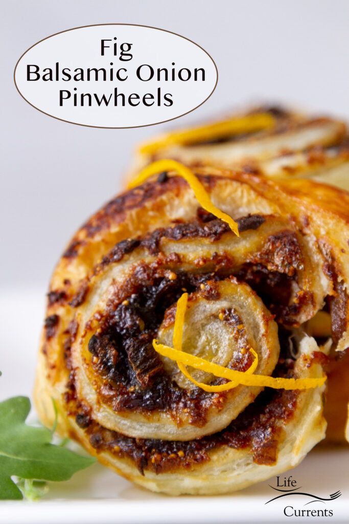 a Fig Balsamic Onion Pinwheels standing on edge garnished with orange zest and arugula.