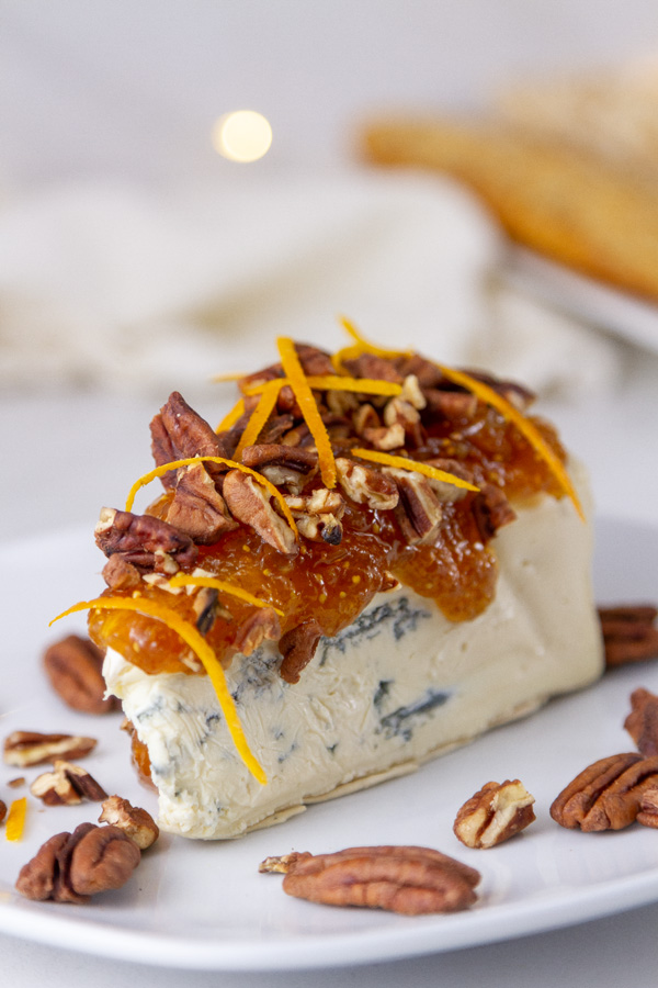 blue cheese with fig jam and pecans in front of a white napkin and some crackers.