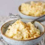 square crop of two light blue bowls of rice pudding, one with a spoon.
