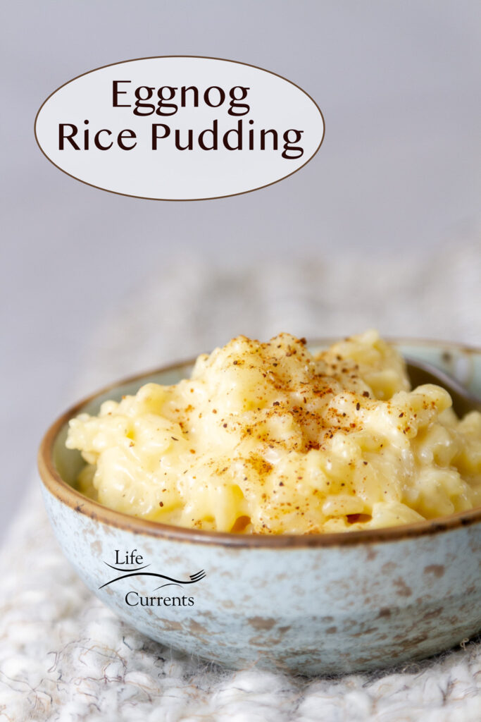 a light blue bowl filled with eggnog rice pudding on a white crocheted place mat.