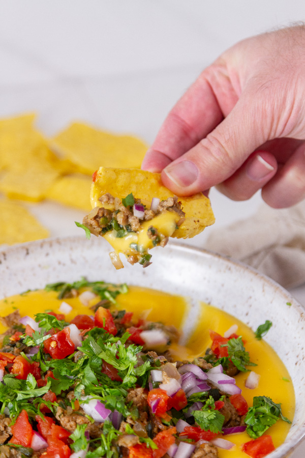scooping up the cheese dip with a tortilla chip.