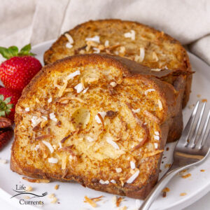 square crop of two slices of Coconut French Toast on a plate with a fork.