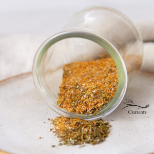 square crop of a glass jar of Cajun Seasoning on its side on a white plate.