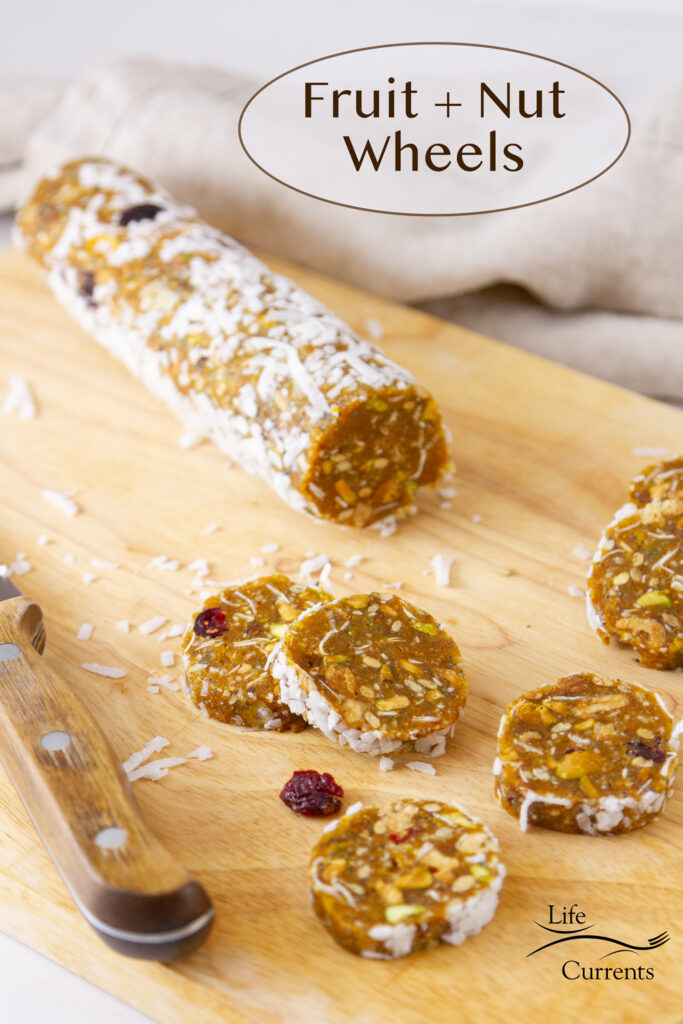 a log of fruits and nuts that's been cut into wheels, the knife is there and there's a napkin in the background.