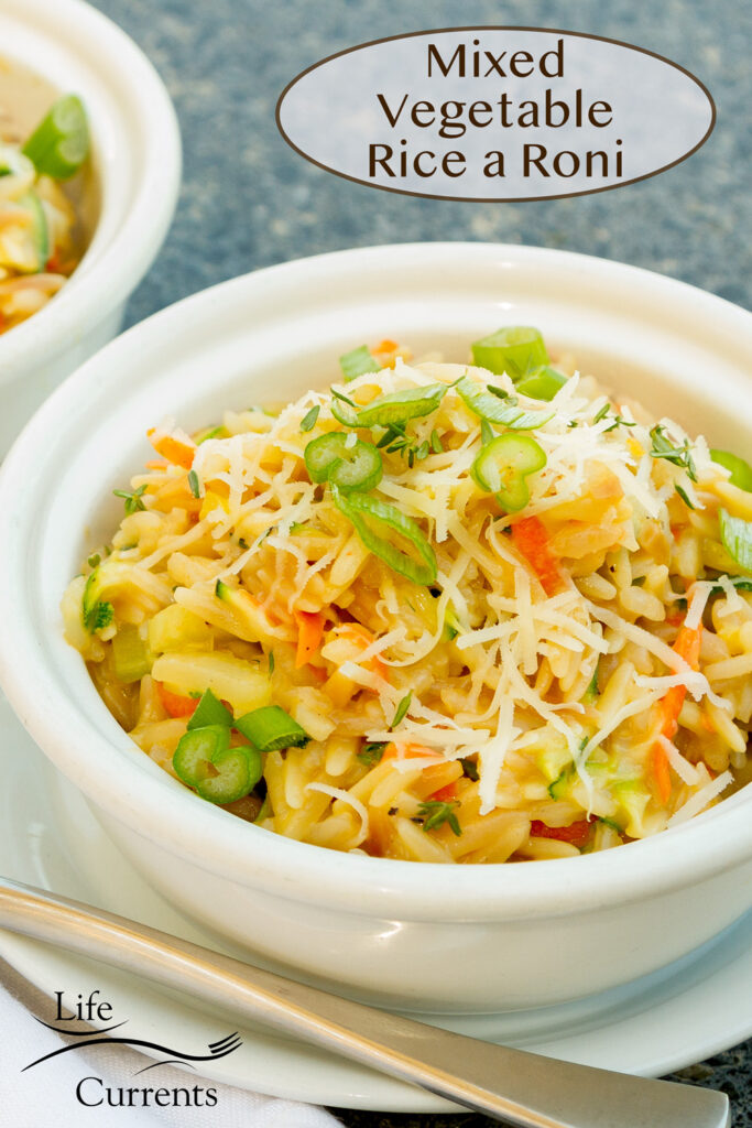 a white bowl filled with vegetables, rice, orzo, and cheese for Mixed Vegetable Rice a Roni.