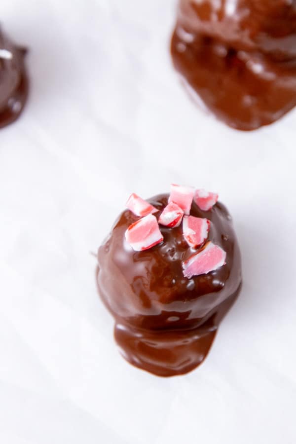 chocolate dipped cookie ball decorated with crushed peppermint candies.