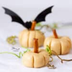 three peanut butter pumpkins with vine tenderils around them and a bat in the background.
