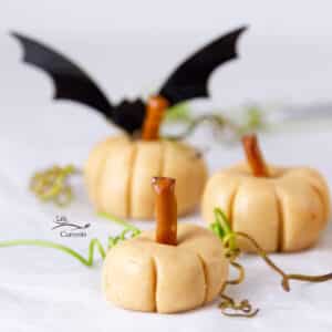 three peanut butter pumpkins with vine tenderils around them and a bat in the background.