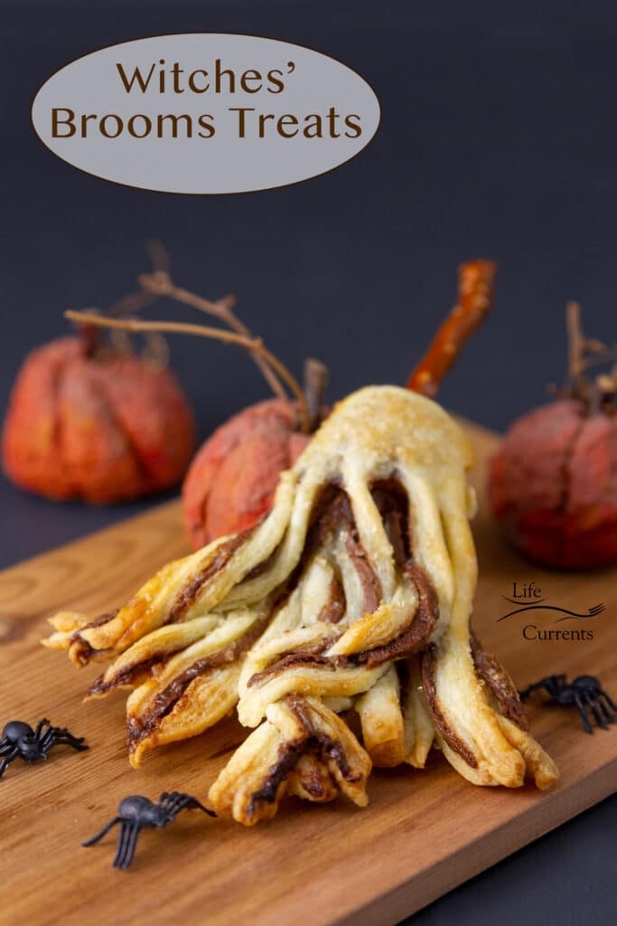 a puff pastry cookie made from a Witches Brooms Recipe with Nutella and a pretzel stick leaning on pumpkins next to plastic spiders.