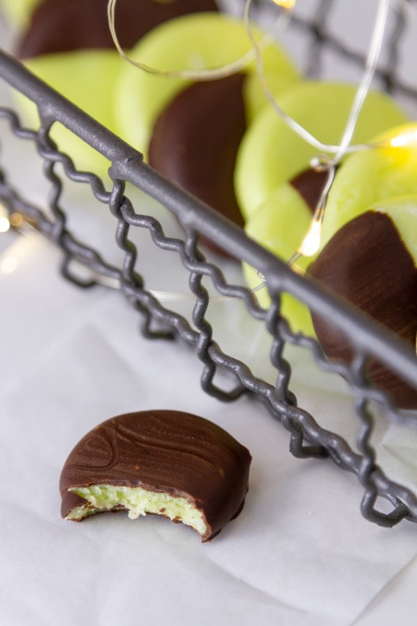Mint candies in a wire tray with one in front that has a bite out of it.