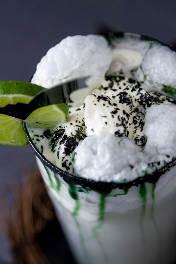close up on the top of a drink topped with whipped cream, bubbles have formed.