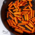 square crop of cooked carrots in a cast iron skillet.
