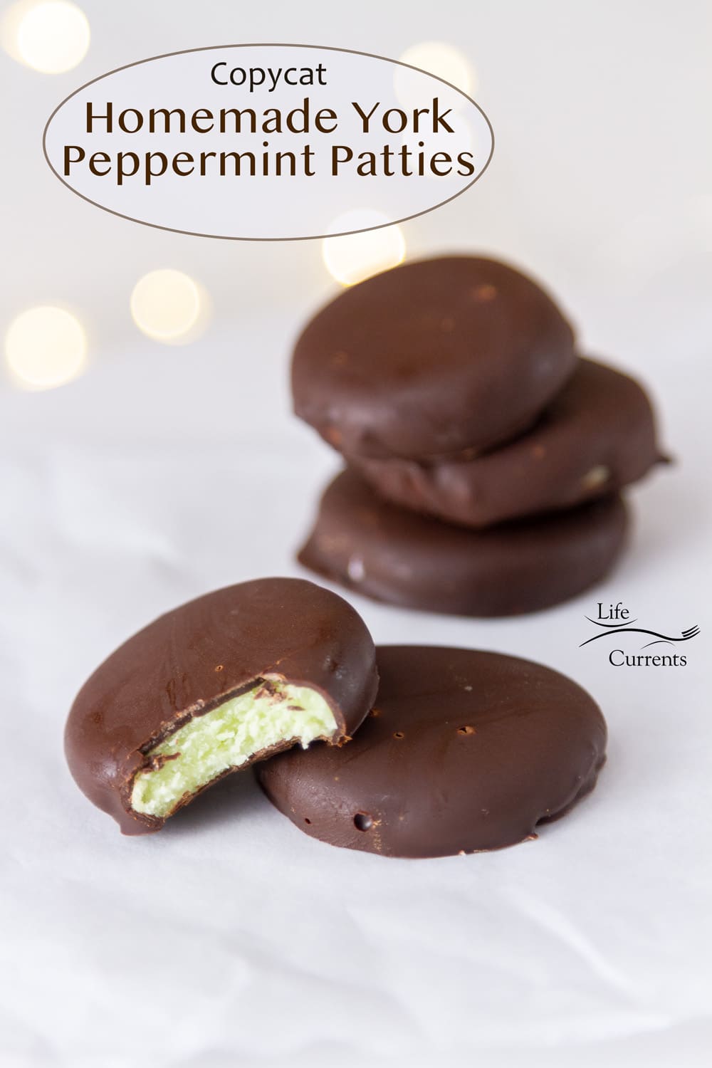 Copycat Homemade York Peppermint Patties stacked up on parchment paper, one has a bite missing.