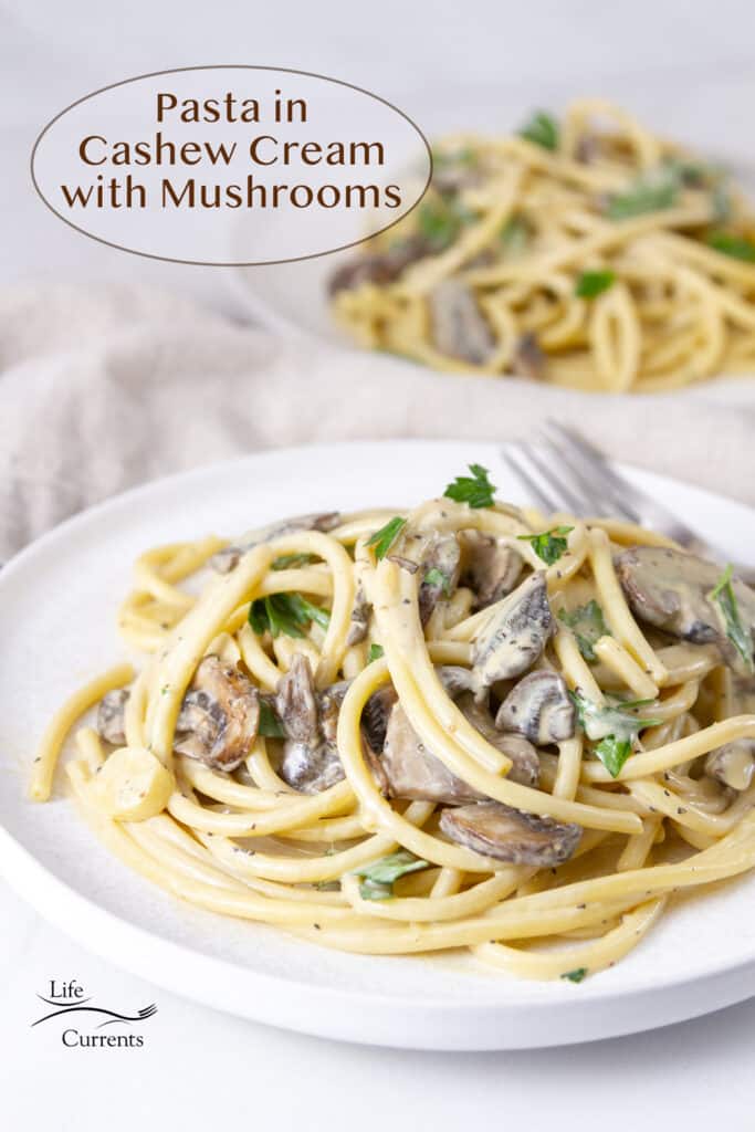 Two white plates with Pasta in Cashew Cream with Mushrooms on them.