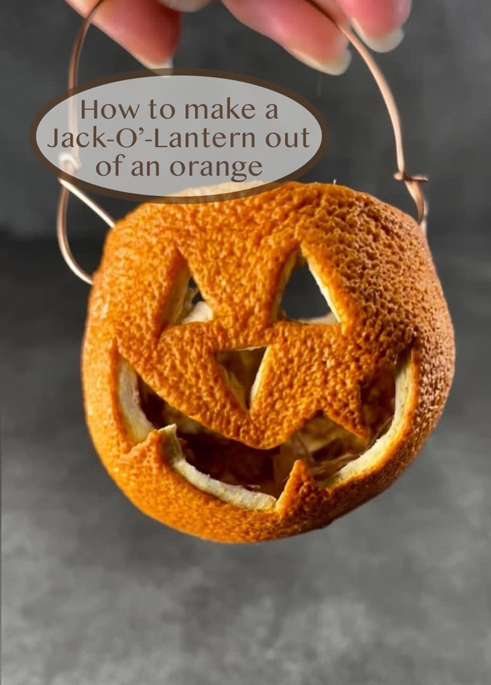 a jack o' lantern made out of an orange being held by my hand.