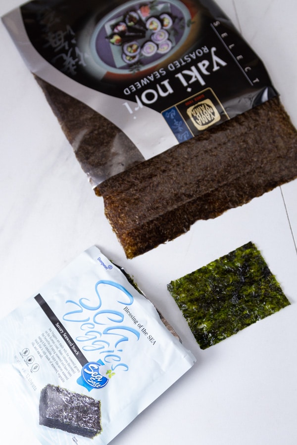 small seaweed snacks in the lower left, and a full sized nori sheet in the upper part of the photo.