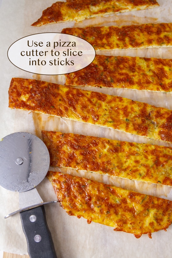 a pizza cutter next to baked cheese sticks.