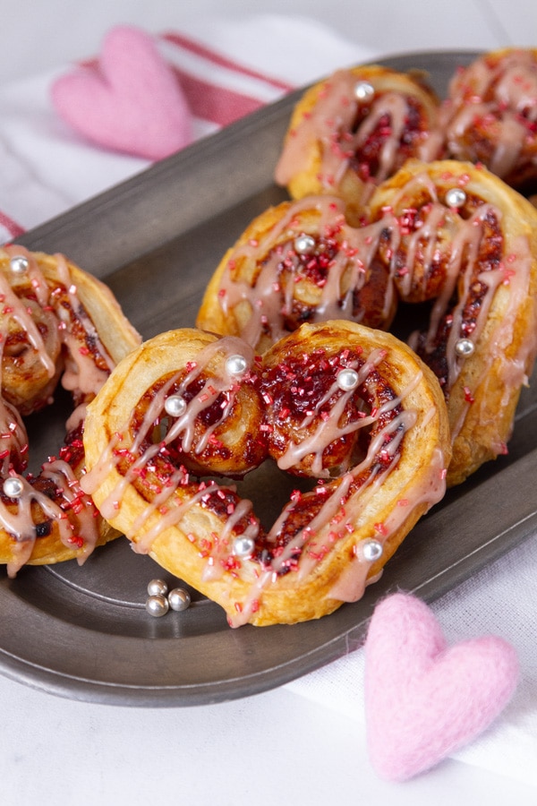 heart shaped raspberry cookies on a pewter plate with small felt hearts around the plate.