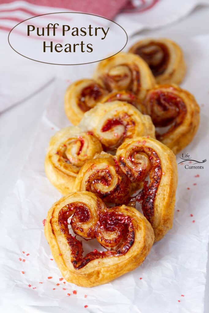 heart shaped puff pastry cookies on a piece of parchment paper with a red striped napkin in the background.