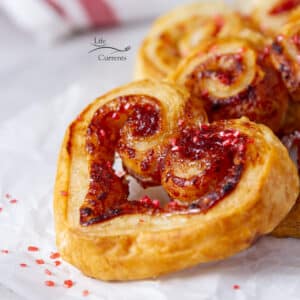 looking at a heart shaped cookie from the side and a red napkin in the background.
