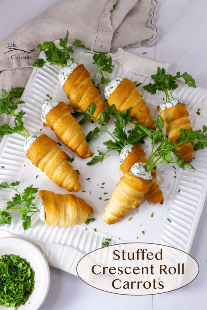 Stuffed Crescent Roll Carrots on a white serving platter with a dish of chopped parsley next to it.