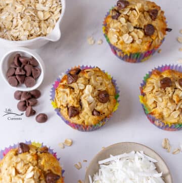 4 peanut butter oatmeal muffins next to bowls of coconut, oatmeal, and chocolate chips.