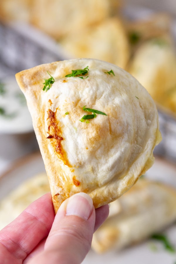 a hand holding an air fried pierogie.