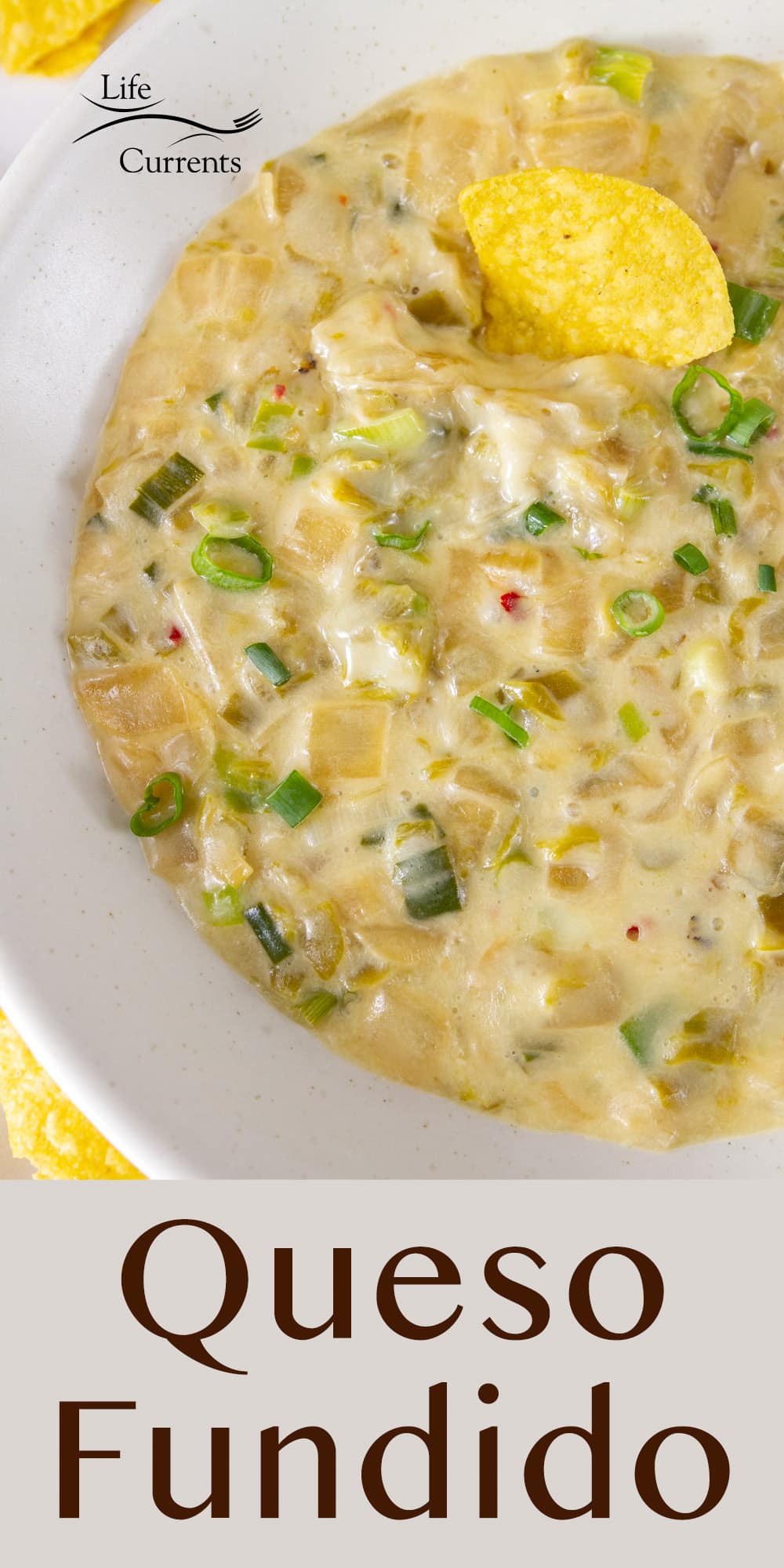 looking down into a bowl of melted cheese dip or queso fundido with green onions and green chiles.