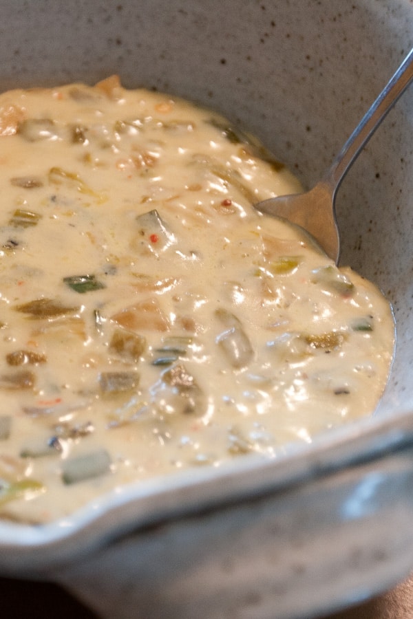 close up on queso fundido in a white bowl with a spoon in it.