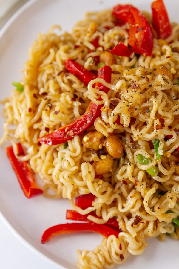 ramen noodles with vegetables and peanuts on a white plate.