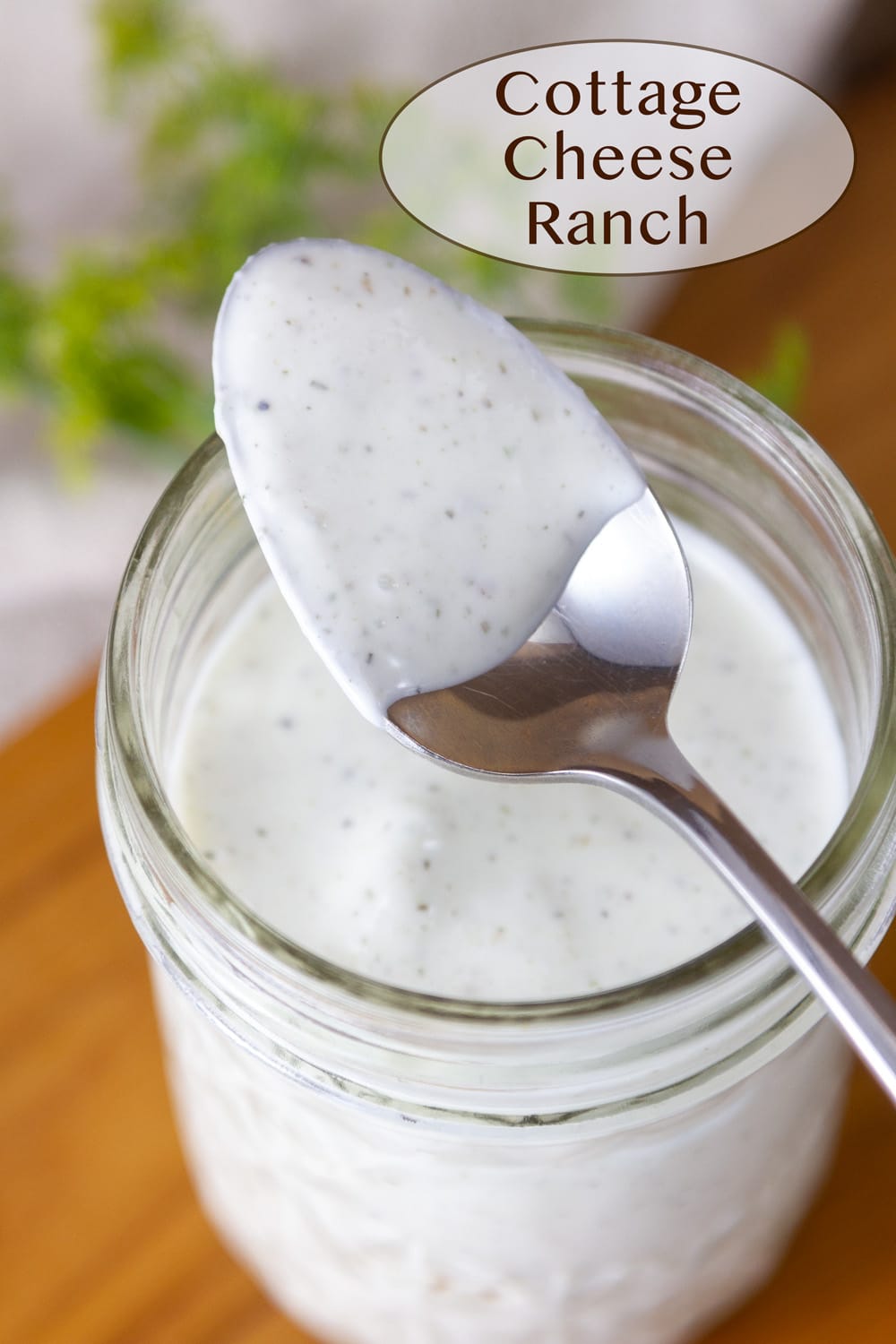 a mason jar filled with cottage cheese ranch dressing and a spoon on top that's been dipped in the dressing.