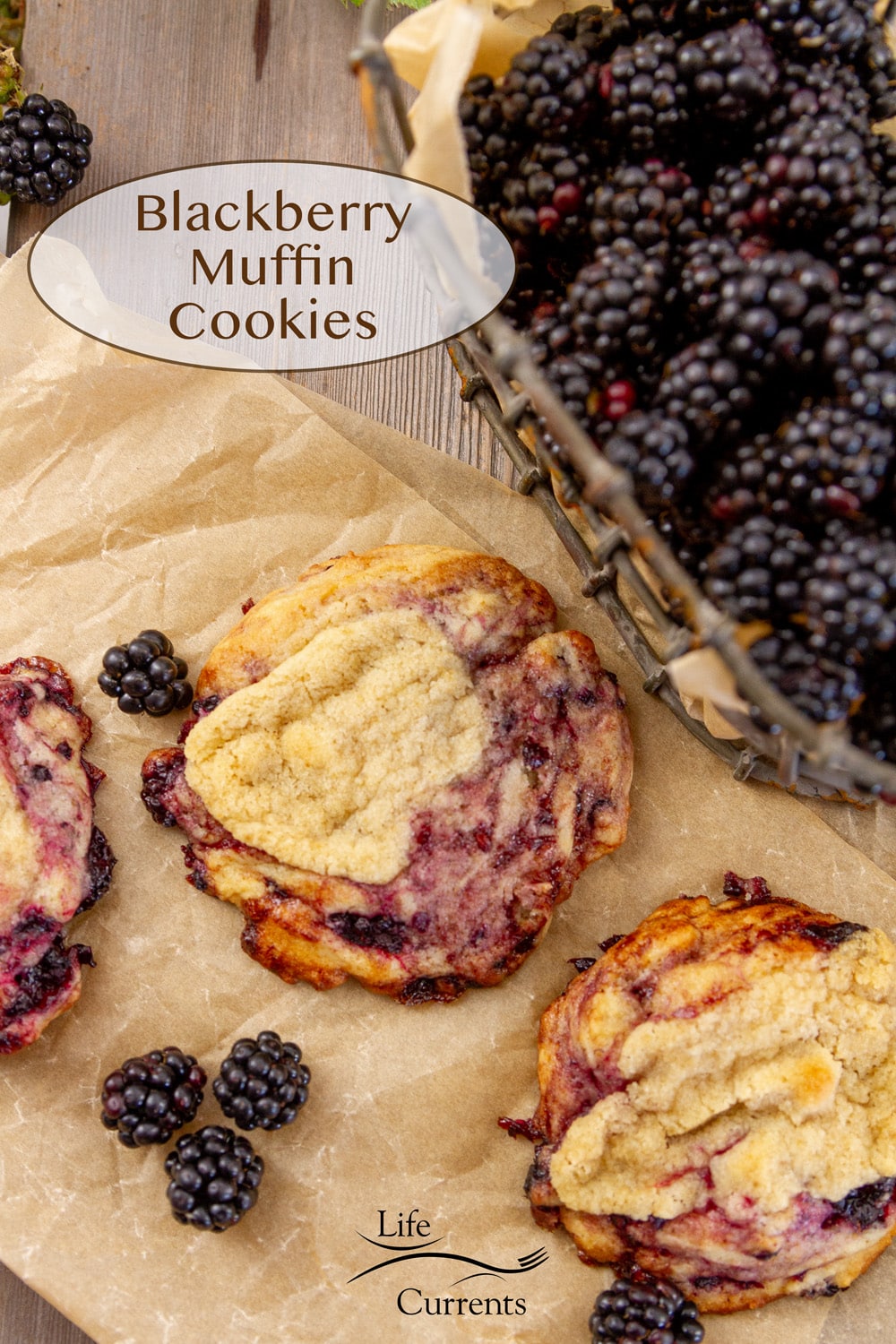 three blackberry swirled cookies on a piece of parchment paper with a basket of blackberries to the upper right.