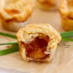 square crop of a fig and brie mini pie that's been bitten open so you can see the inside with chives behind it.