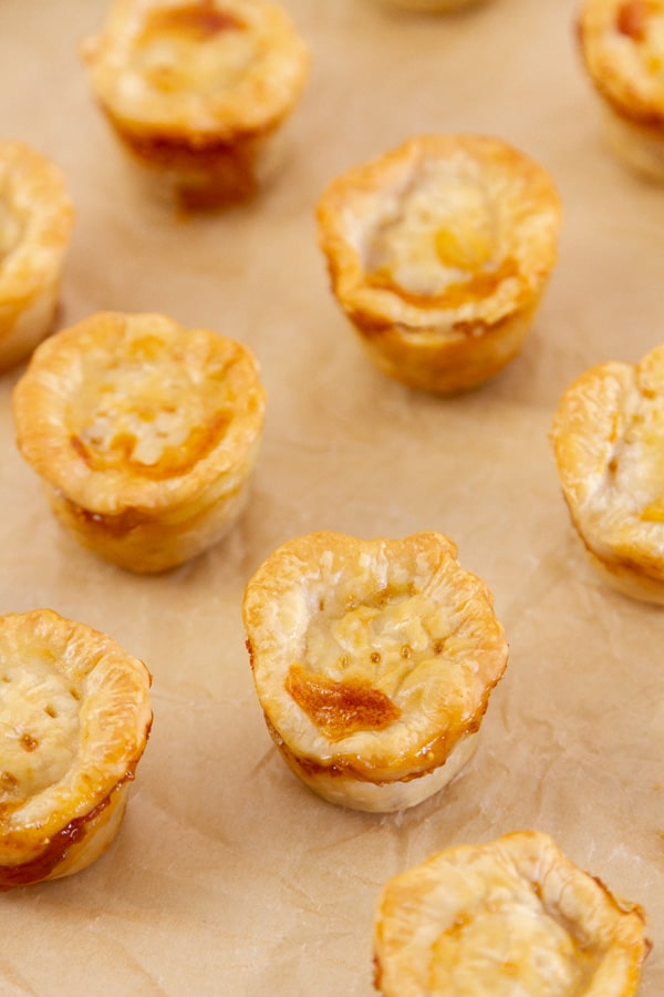 looking down on a bunch of mini tarts on a brown piece of parchment paper.